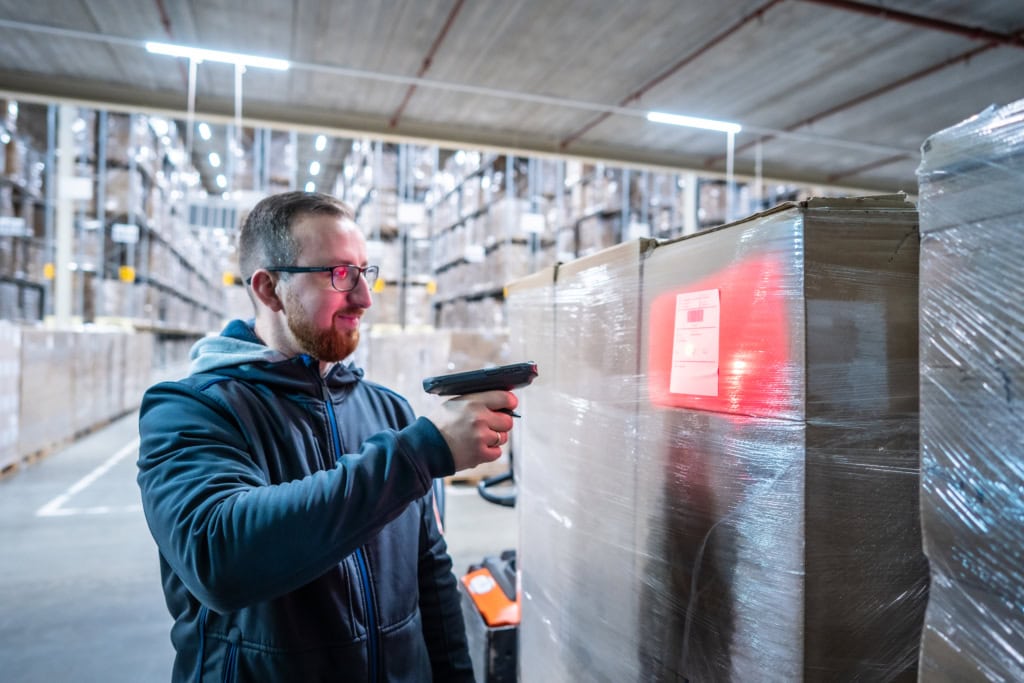 Mann scannt Pakete im Lager